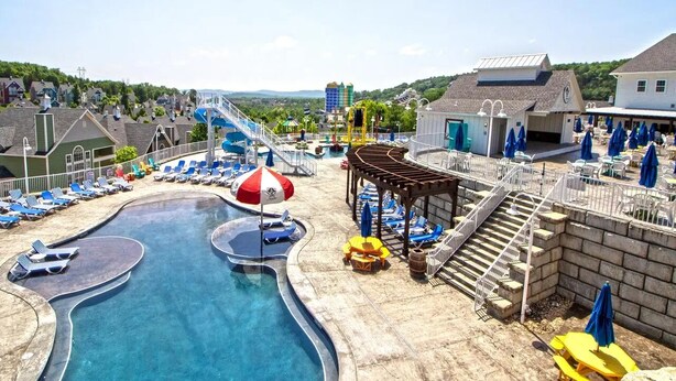 Une piscine avec des chaises longues, un toboggan aquatique et un espace détente abrité.