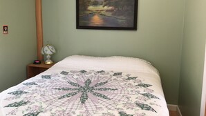 Une chambre à coucher avec un lit, un tableau, une table de chevet et une lampe.