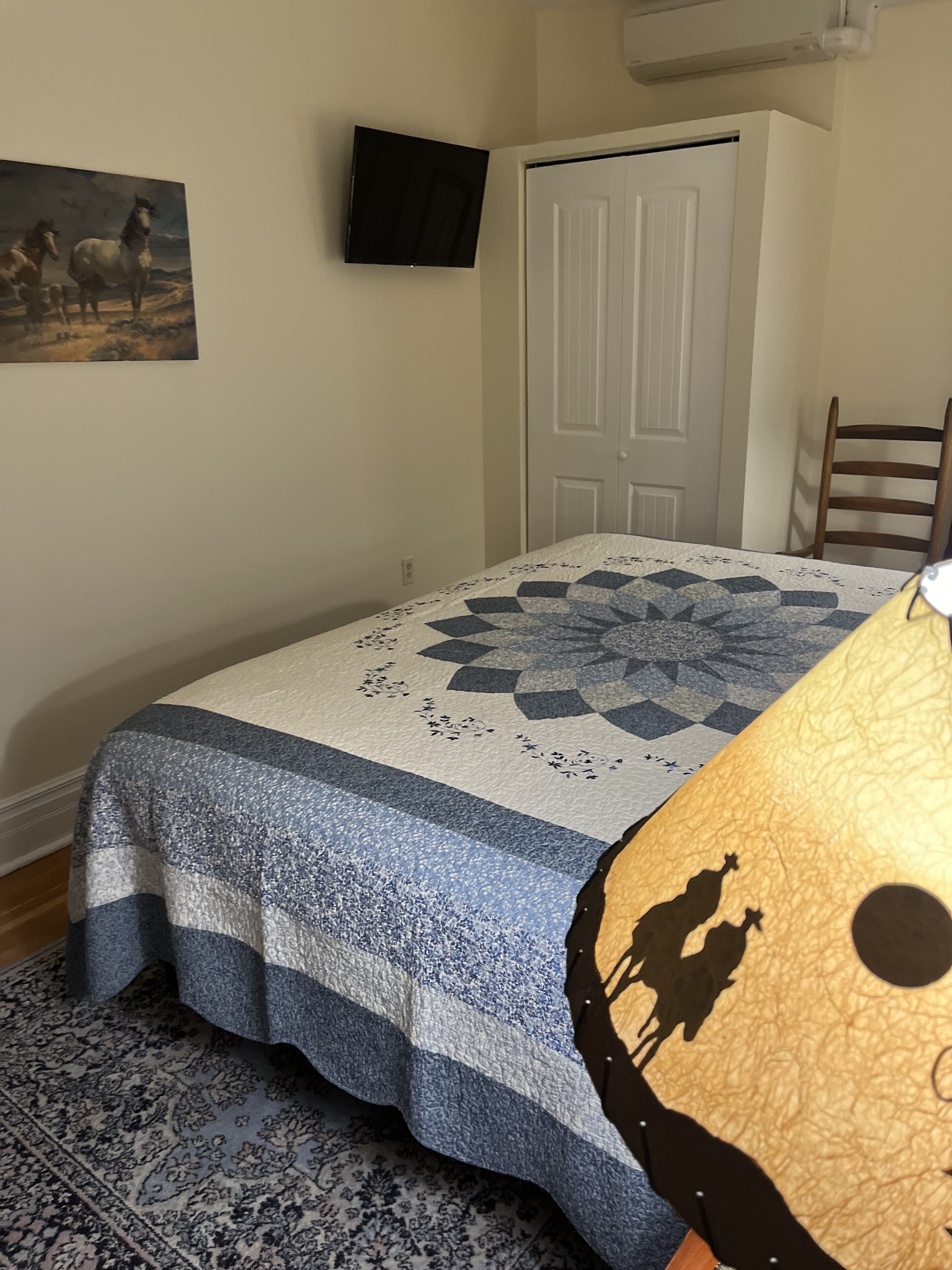 Quarto com cama, quadro, televisão e porta.