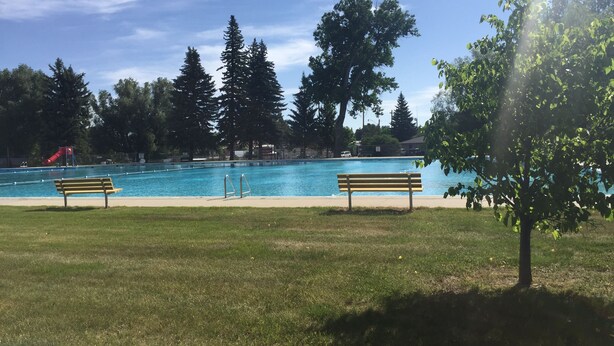 A swimming pool with two benches, surrounded by grass and trees. - King One Bedroom, Converted 1894 Historic Hotel, Downtown Buffalo Wyoming (Buffalo)