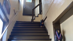 A wooden staircase with a metal handrail, a sign indicating a linen room, and a statue with a medal. - King One Bedroom, Converted 1894 Historic Hotel, Downtown Buffalo Wyoming (Buffalo)