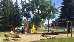 A playground with slides and swings, surrounded by trees and a picnic table. - King One Bedroom, Converted 1894 Historic Hotel, Downtown Buffalo Wyoming (Buffalo)