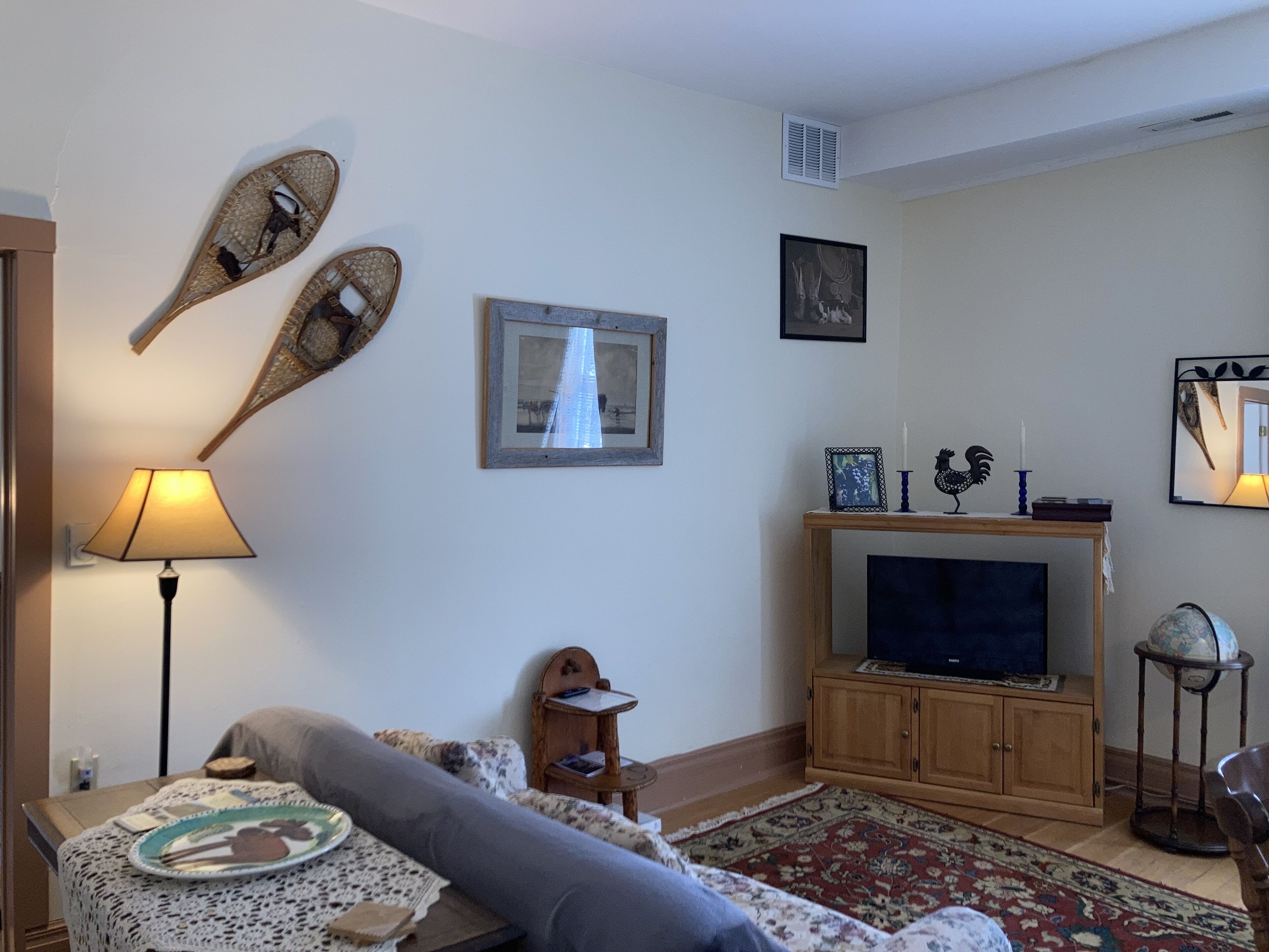 A living room with a sofa, a television, a lamp, and decorative items on the wall.