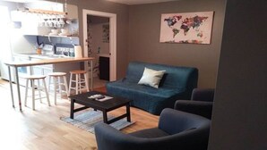A living room with a sofa, a coffee table, and two chairs. There is a kitchen area with a bar stool and a counter. A world map is displayed on the wall. - Wine Alley West Suite (Hermann)