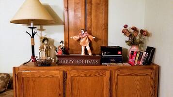 A wooden cabinet with a 'HAPPY HOLIDAYS' sign, a lamp, a small figurine, and a vase with dried flowers.