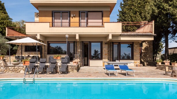 A two-story house with a swimming pool, outdoor seating, and a stone facade. - Modern Panoramic Villa with swimming pool in Florence - Tuscany (Firenze)