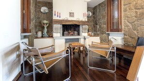 A room with a stone wall, a fireplace, and two metal-framed chairs. - Modern Panoramic Villa with swimming pool in Florence - Tuscany (Firenze)