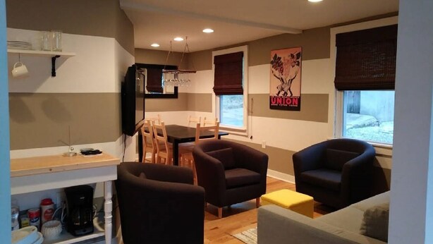 A modern living room with a dining area, featuring a sofa, armchairs, a coffee machine, and a TV. - The House on Wine Alley (Hermann)