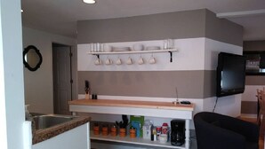 A modern kitchen with a built-in oven, a coffee machine, and a shelf with kitchen essentials. - The House on Wine Alley (Hermann)