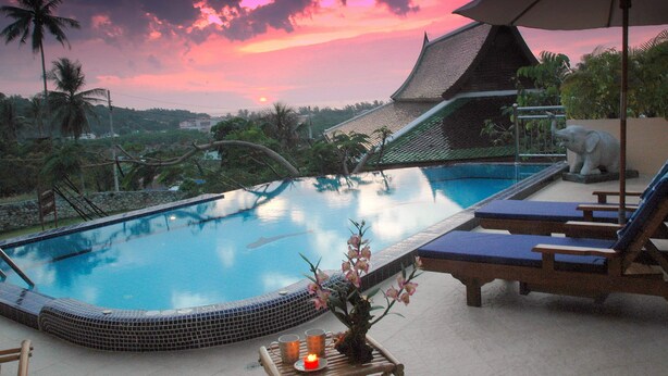 A swimming pool with a tiled edge, lounge chairs, and a decorative plant.