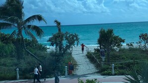 Ein Balkon mit Blick auf das Meer, ein Weg zum Strand und ein weißer Stuhl.