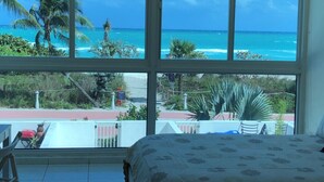 Ein Zimmer mit großem Fenster und Blick auf Strand und Meer.