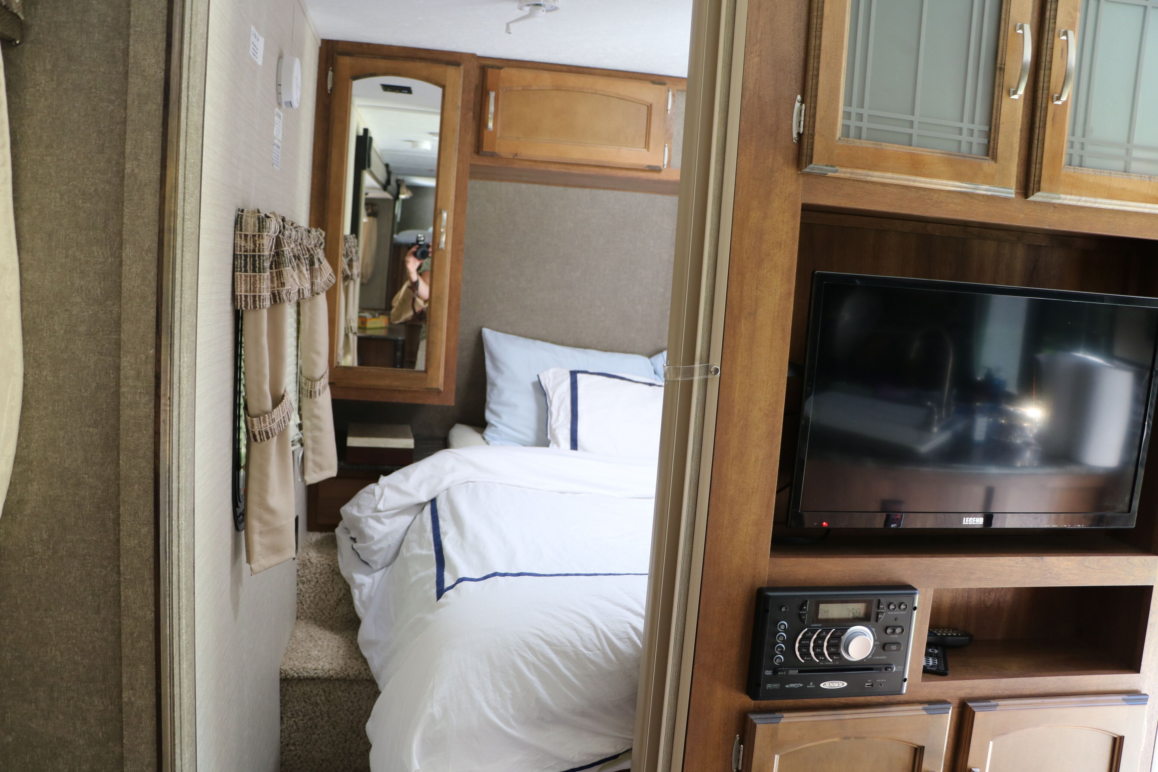 A compact bedroom with a bed, a television, and a radio.
