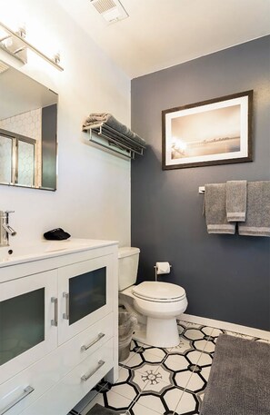 Un baño moderno con tocador blanco, inodoro y zona de ducha.
