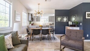 A modern living room with a sofa, a coffee table, and a dining area with a table and chairs. - Movie Colony Home with Private Casita, Pool & Spa! (Palm Springs)