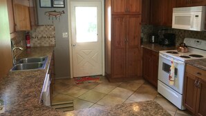 Une cuisine dotée de plans de travail en granit, de meubles en bois, d’une cuisinière blanche et d’un four à micro-ondes.