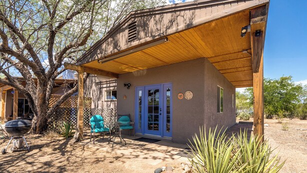 Un'area esterna coperta con patio, una griglia per barbecue e una porta blu.