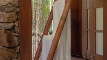 A wooden staircase with a white towel hanging on the railing, a stone wall, and a wooden door with glass panels.