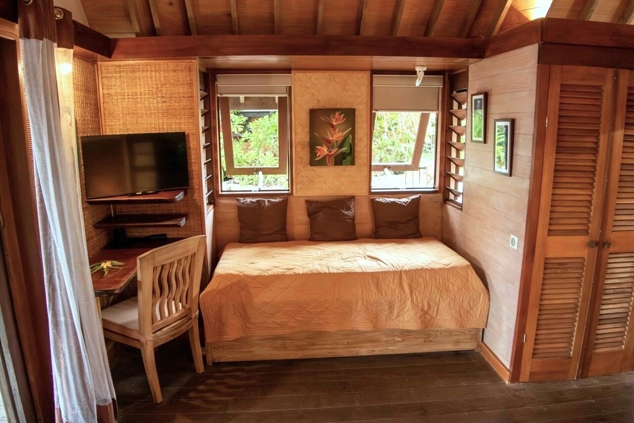 Een kamer met een bed, een televisie en een raam met uitzicht op groen.