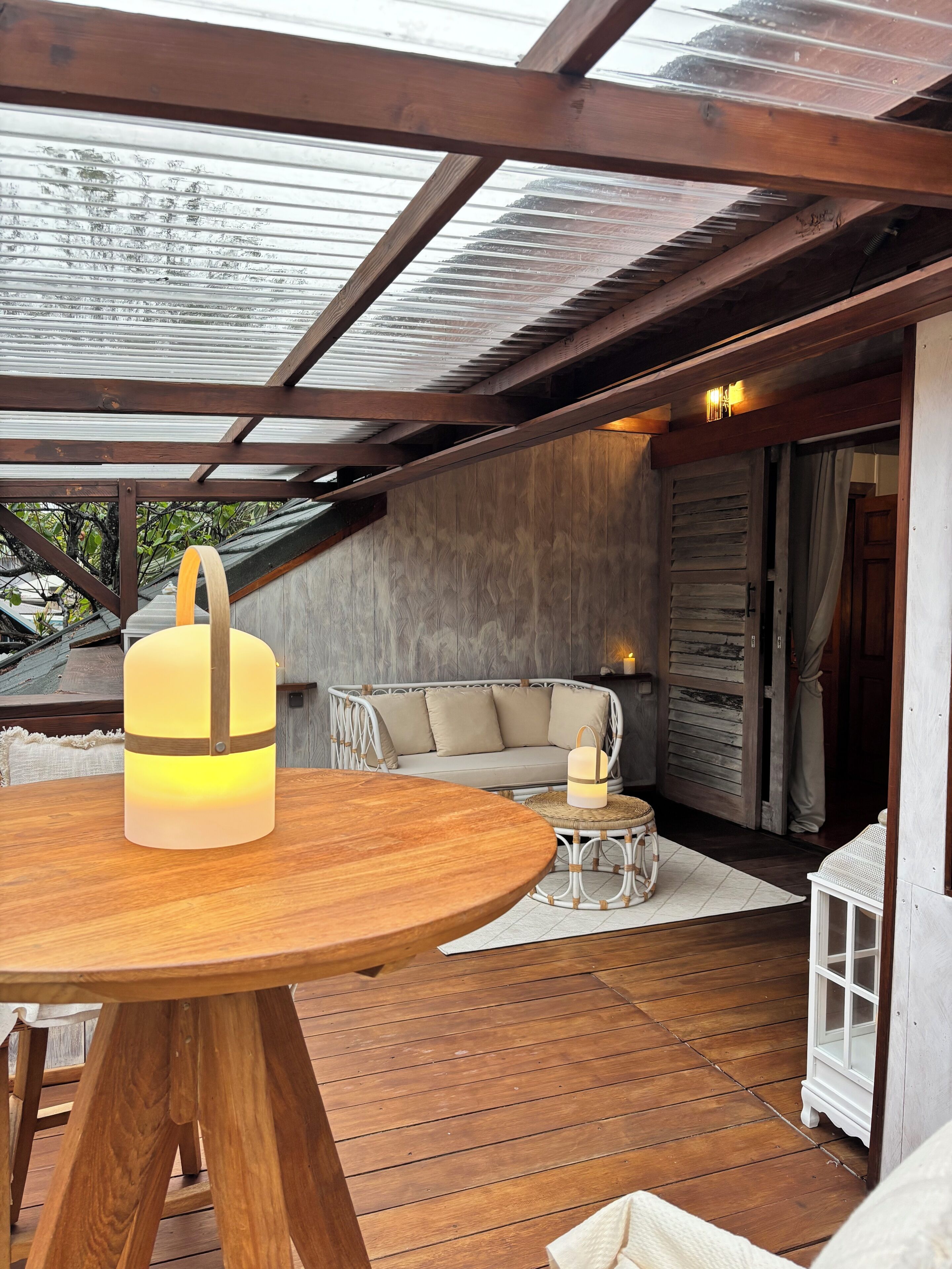Terraza de madera con una mesa redonda y un farol colgante.