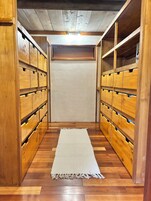 Un cuarto de almacenamiento de madera con múltiples compartimentos, un tapete tejido blanco en el suelo y una lámpara en el techo.