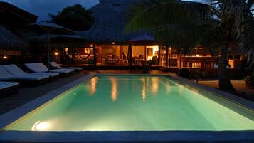 Relax by the serene pool surrounded by lounge chairs and umbrellas, with comfortable rooms nearby.