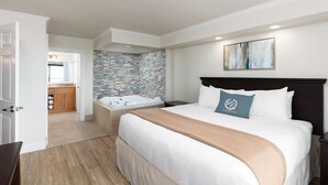 A modern hotel room with a large bed, a separate bathroom with a bathtub, and a view of the adjacent kitchen area. -  Special Exceptional Offer Guaranteed Oceanfront Villa  Available July 11-18 (Myrtle Beach)
