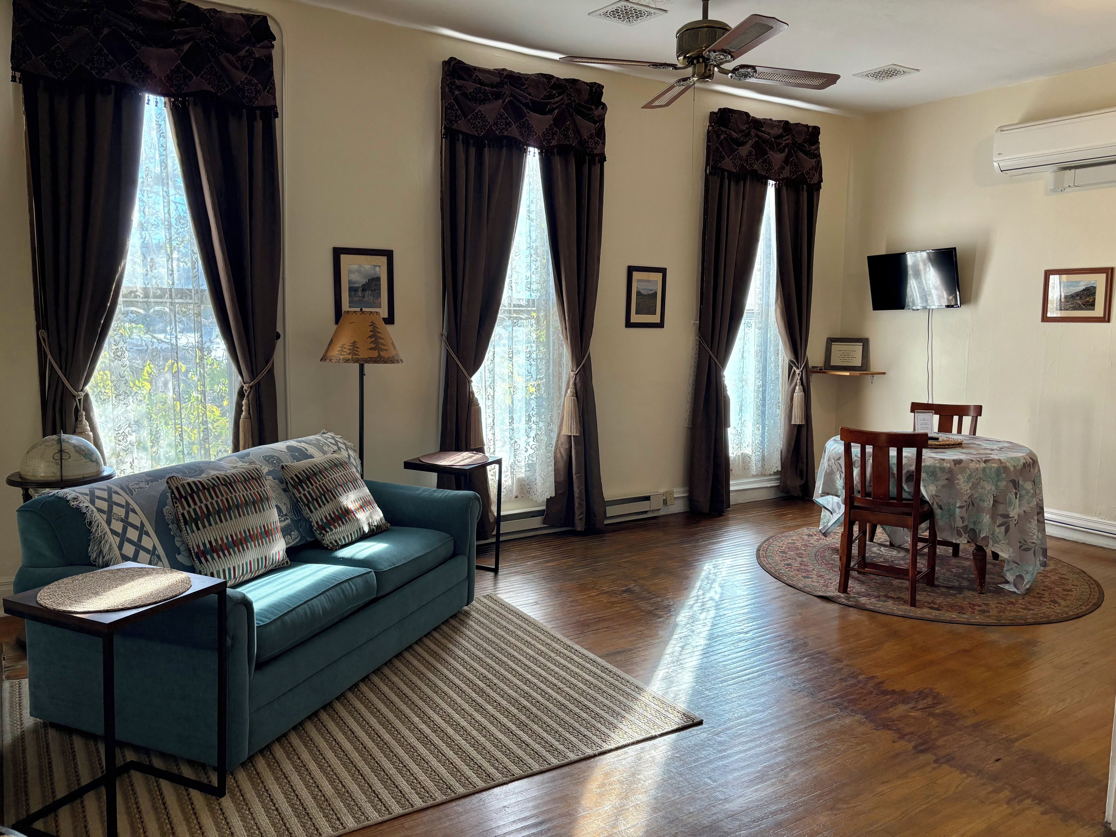 A living room with a sofa, a dining table, and a ceiling fan.