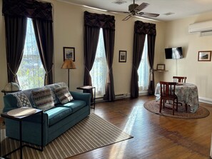 A living room with a sofa, a dining table, and a ceiling fan.