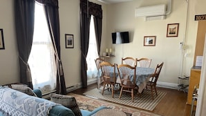 A living room with a blue sofa, wooden chairs, a dining table, and a TV. - King One Bedroom, Converted1894 Historic Hotel, Downtown Buffalo Wyoming (Buffalo)