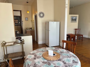 A compact living space with a dining area, kitchen, and a refrigerator.