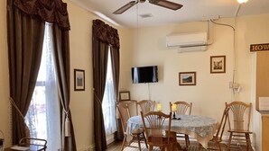 A dining area with a table, chairs, a ceiling fan, and a mounted TV. - King One Bedroom, Converted1894 Historic Hotel, Downtown Buffalo Wyoming (Buffalo)