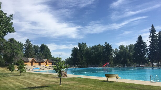 A swimming pool with a red slide, surrounded by a grassy area and trees. - King One Bedroom, Converted1894 Historic Hotel, Downtown Buffalo Wyoming (Buffalo)