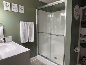 Un baño con cabina de ducha de vidrio, un lavabo blanco y un perchero para toallas.