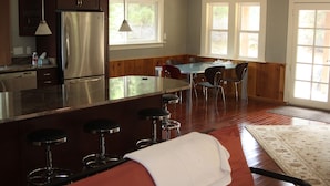 Eine moderne Küche mit Edelstahlkühlschrank, Holzschränken und einer Bar mit Hockern.