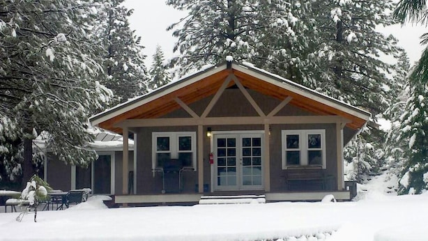 Eine Lodge mit Holzwand, großen Fenstern und einer überdachten Veranda.