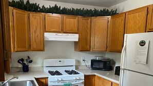 A kitchen with wooden cabinets, a white stove, a microwave, and a refrigerator. - 3 Bedroom, 1 Bath Peaceful Lodge Just Minutes From The Kenai River and Soldotna! (Soldotna)