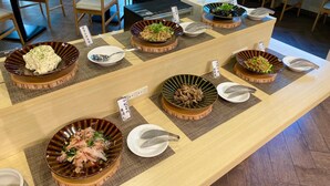 A buffet setup with various dishes displayed on a long table, surrounded by chairs and tables.