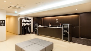 A hotel reception area with a reception desk, a seating area, and a wall with a pillow display.