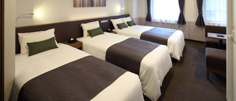 A hotel room with two beds, a desk, and a window with curtains.