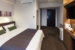 Una habitación de hotel con una cama, un escritorio con cafetera y un televisor.
