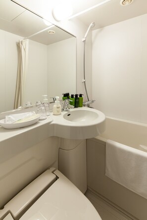Un baño moderno con lavamanos, espejo y ducha blancos.