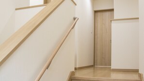 A staircase with wooden handrails and beige steps leading to a door. - Koko (Fujikawaguchiko)