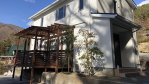 A two-story building with a white exterior and a wooden pergola in front. - Koko (Fujikawaguchiko)