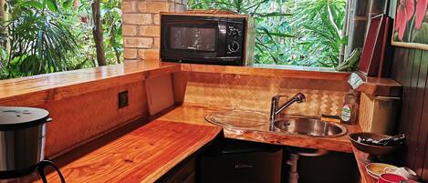 A compact kitchen with a wooden countertop, a stainless steel sink, a microwave, and a coffee maker.