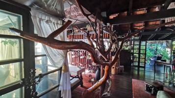 Una habitación con una gran escultura de árbol, muebles de madera y vistas a un jardín.