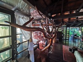 Una habitación con una gran escultura de árbol, muebles de madera y vistas a un jardín.