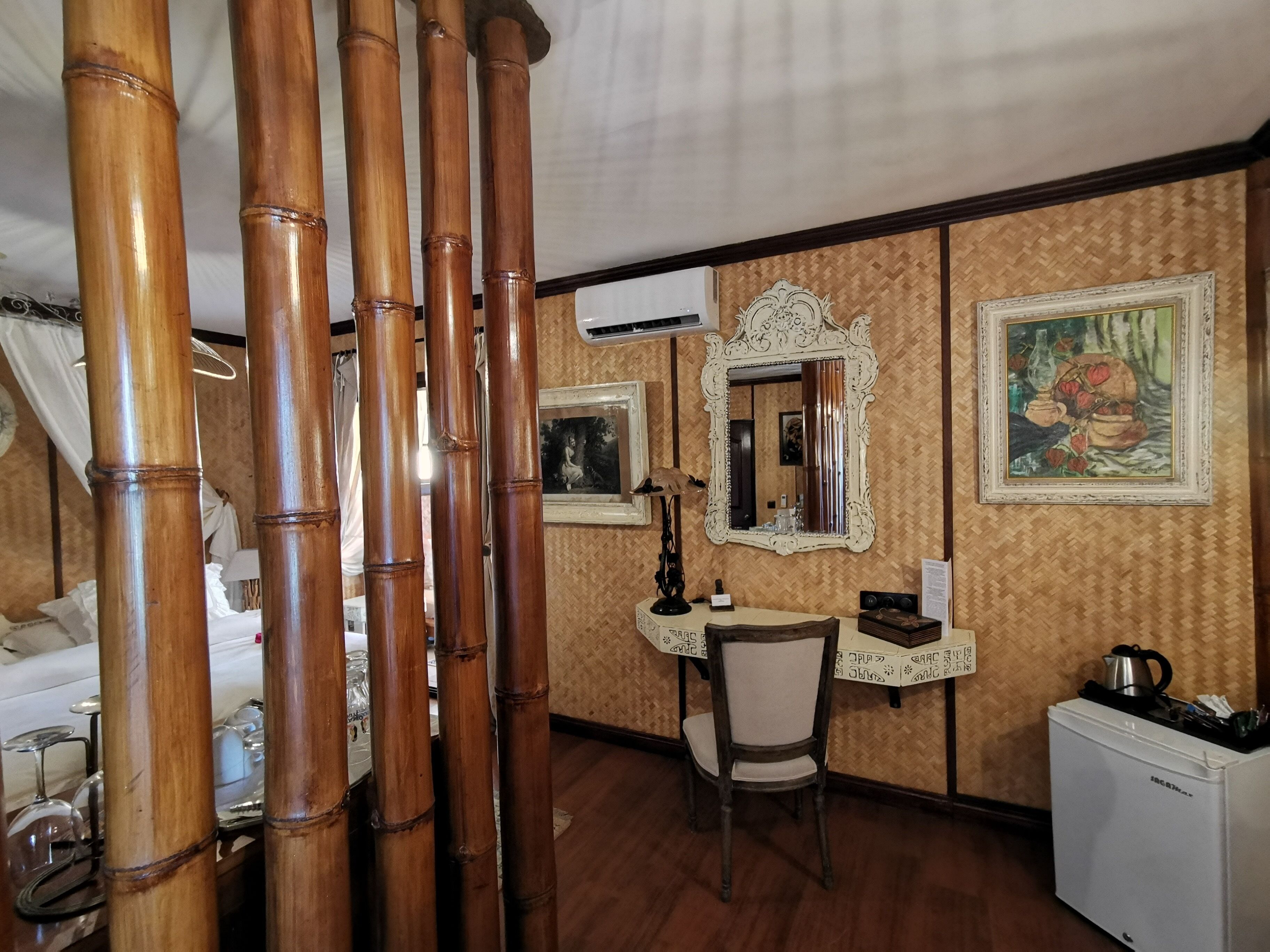 A room with a bed, a desk, a chair, a mirror, and a refrigerator.