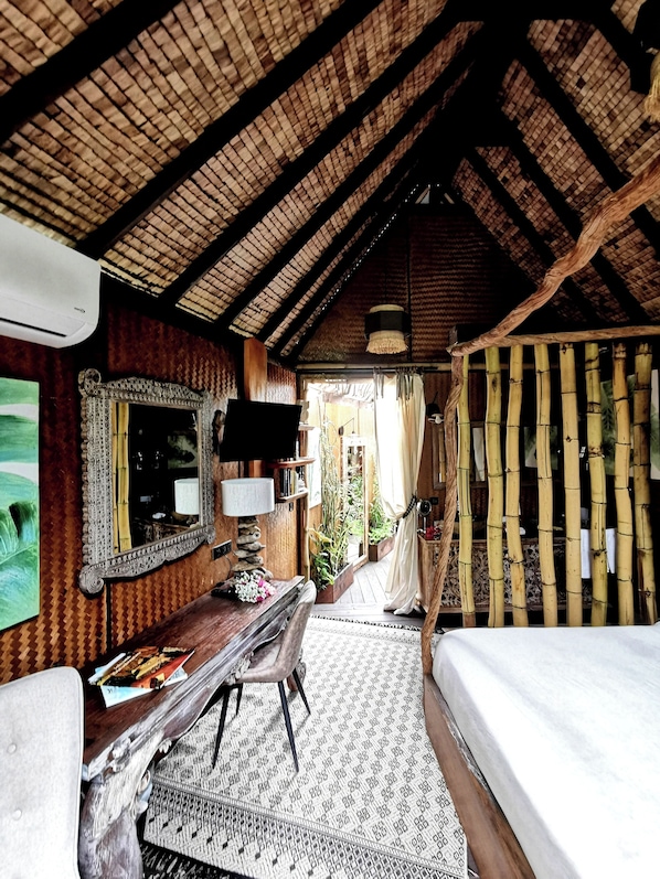Una habitación rústica con techo de madera, una cama, un escritorio con silla, un espejo y una ventana con cortinas.