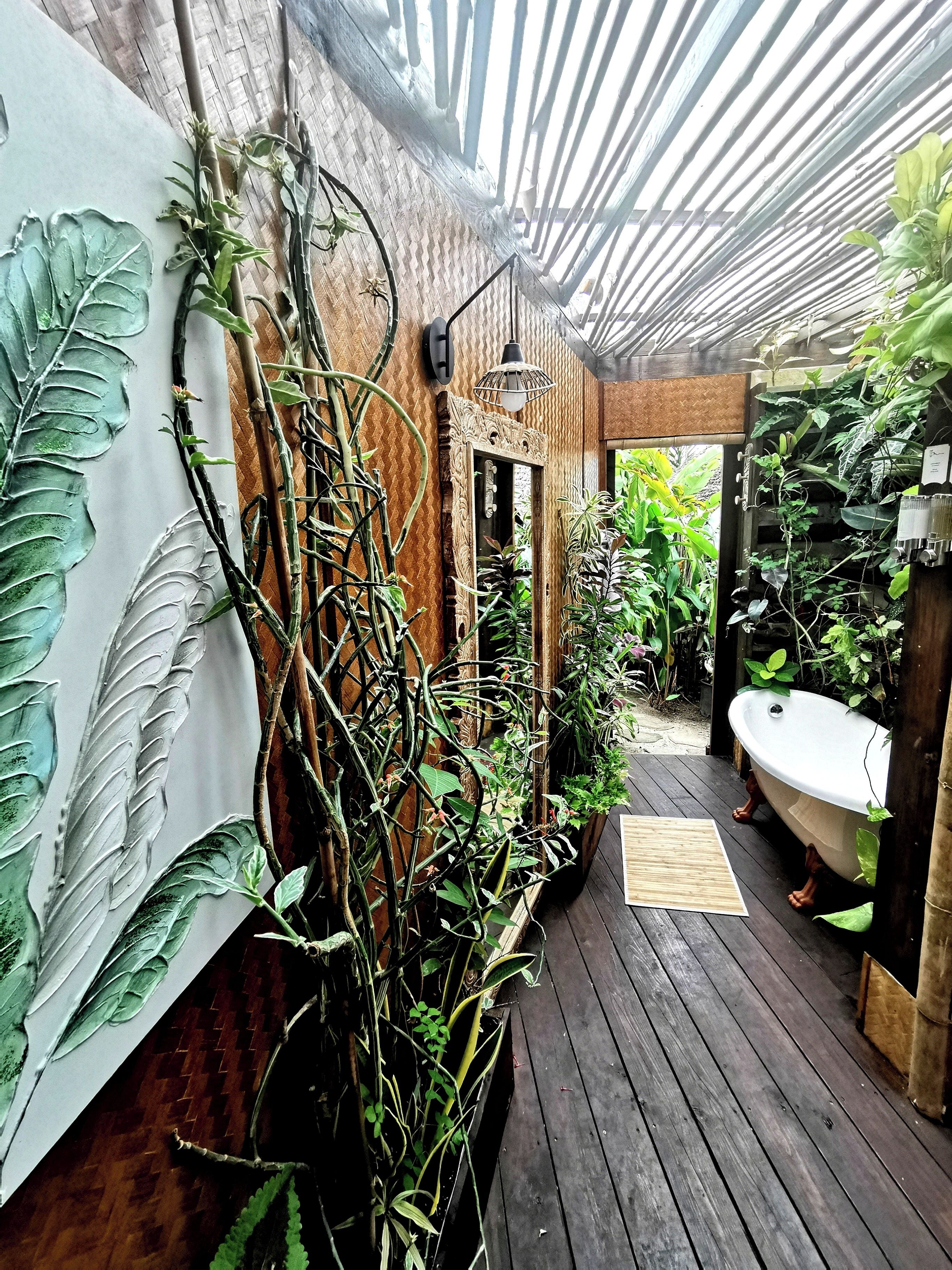 A wooden deck with a white bathtub, surrounded by lush greenery and a wooden wall with leaf patterns.